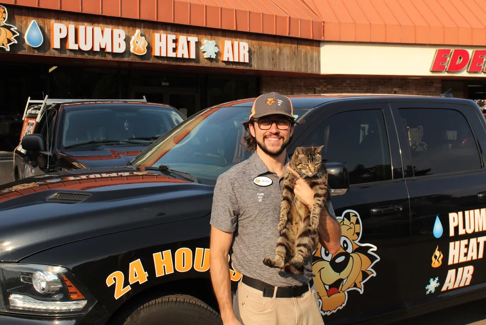 Brady, a Tiger technician, holding Milo in front of Tiger service trucks